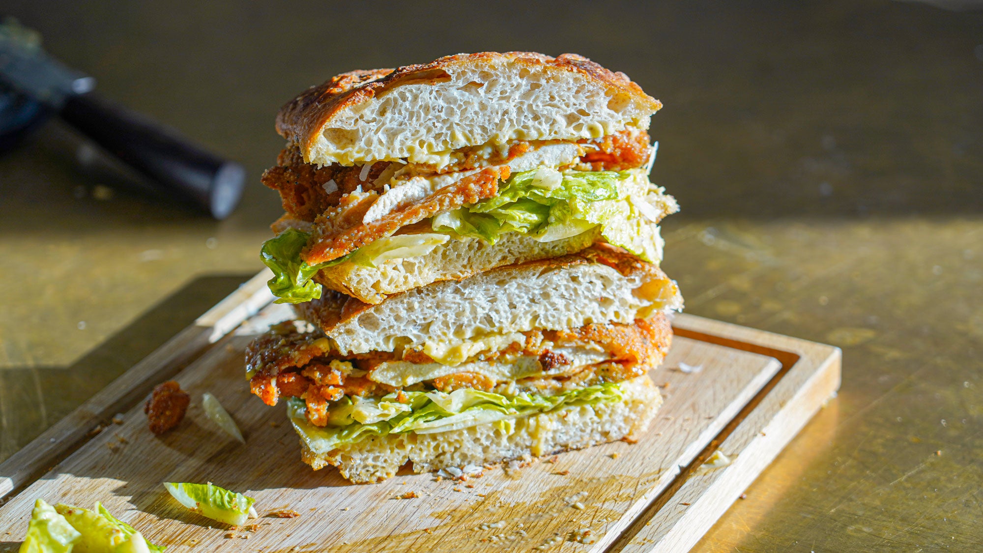 Caesar sandwich med friteret kylling anrettet på skærebræt