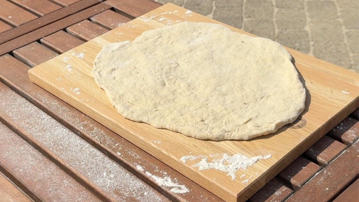 Koldhævet pizzadej på skærebræt i egetræ