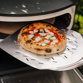 Pizza på pizzaspade på vej ud af pizzaovn