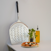 Pizzaspade på bord med pizza