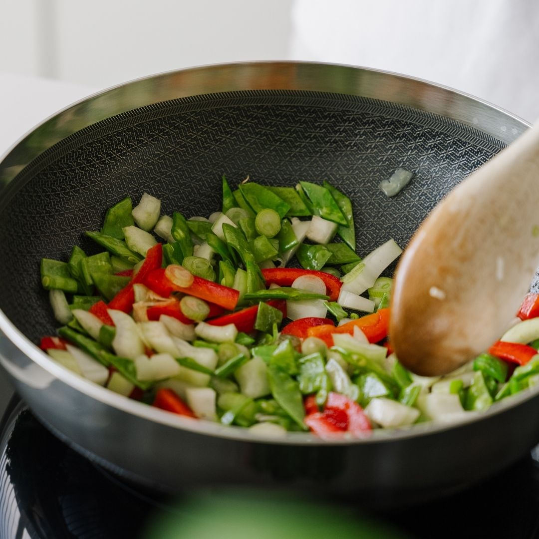 Wok med grøntsager på komfur 